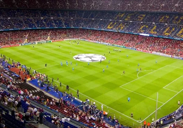 Pełny stadion podczas meczu Ligi Mistrzów UEFA z gigantycznym logo na środku koła