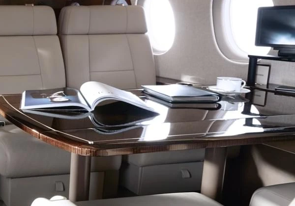 Luxurious private jet cabin with beige seats, glossy table and designer magazine