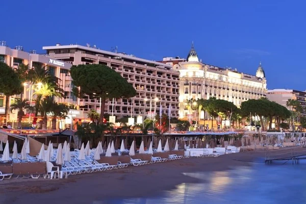 Una playa privada en Cannes por la noche con el palacio Intercontinental Carlton iluminado en la Croisette