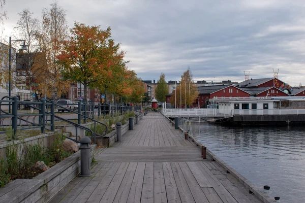 Promenade en bord de mer avec une promenade en bois, des arbres d'automne et des bâtiments rouges traditionnels à Helsinki, Finlande