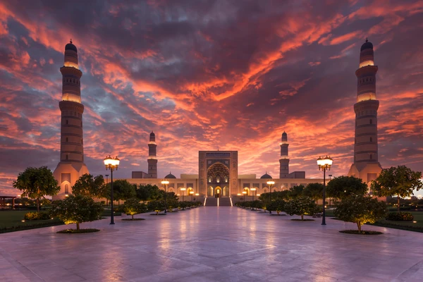 Dramatischer Sonnenuntergang über der Al-Hakim-Moschee in Kairo, Ägypten, mit beleuchteten Minaretten und spiegelndem Innenhof in der Abenddämmerung