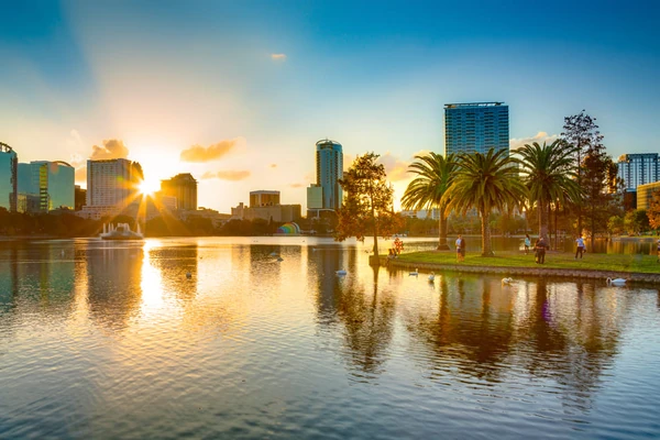 Orlando skyline au coucher du soleil se reflétant sur le lac avec fontaine et palmiers