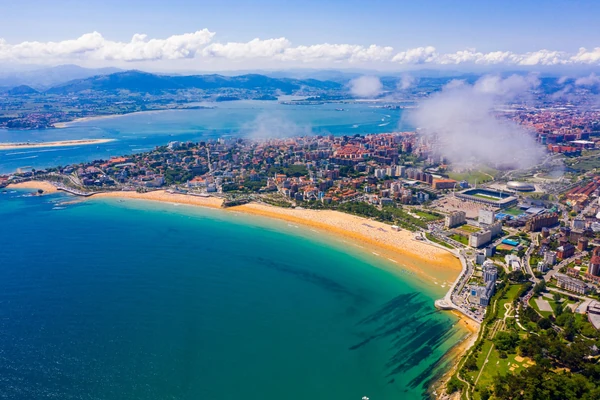 Aerial view of Benidorm's golden sandy beach, turquoise Mediterranean waters, and coastal cityscape with mountains in background