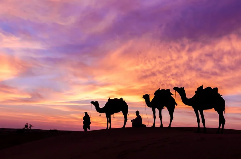 Sivatagi ember tevével és kiterjedt égbolttal