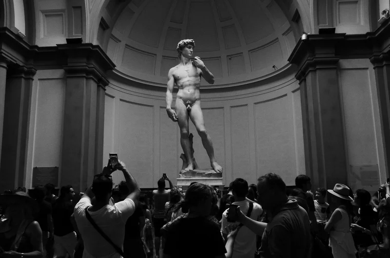 Turyści patrzą na Dawida Michała Anioła w Accademia di Belle Arti di Firenze we Włoszech