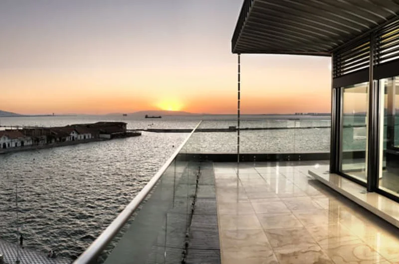 Taras na dachu z widokiem na morze o zachodzie słońca ze szklaną balustradą