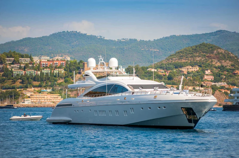 Nyáron a franciaországi Cannes-öbölben horgonyzó nagy fehér motoros jacht, a felső fedélzeten párnákkal a vendégek számára