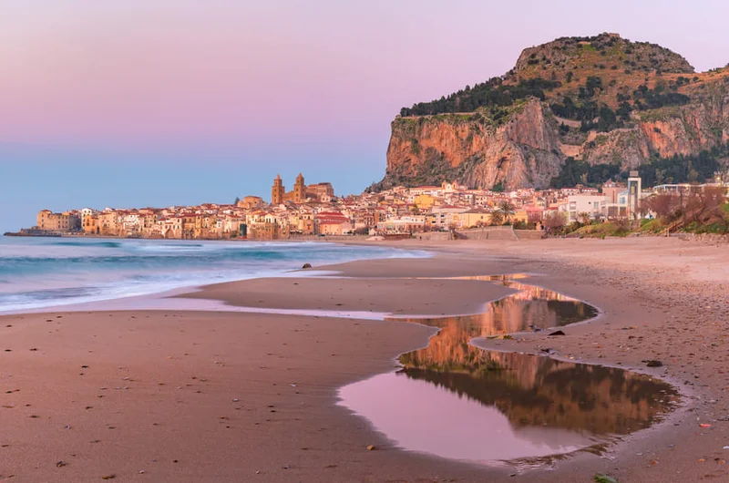 Panorámás kilátás a tengerpartra, a Cefalù-székesegyházra és Cefalù tengerparti városának óvárosára rózsaszín naplementében, Szicília, Olaszország