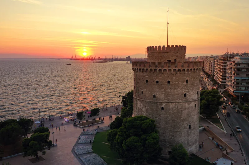 Widok z lotu ptaka na Białą Wieżę w Salonikach, historyczny punkt orientacyjny Bizancjum, o zachodzie słońca w złotych kolorach, północna Grecja