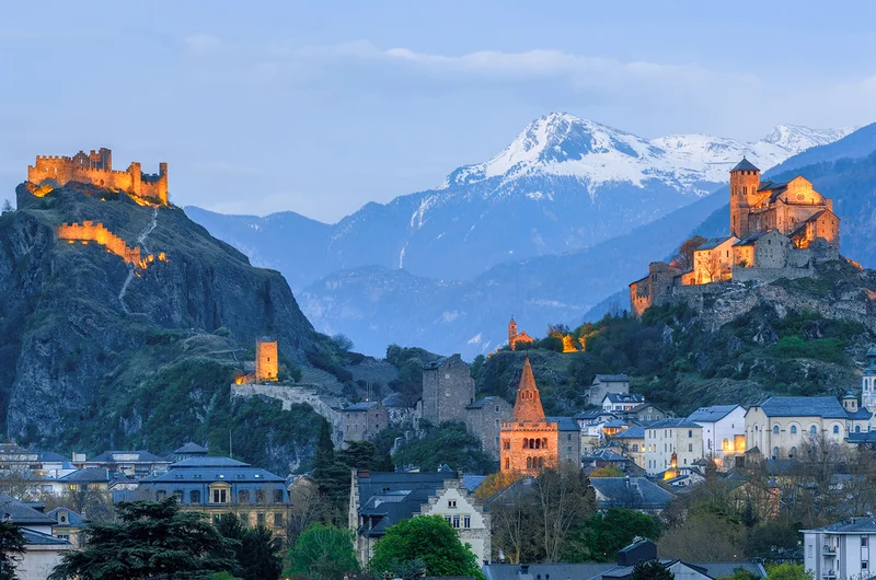 Emberek egy gyalogos utcában egy napsütéses nyári napon, erős fényben Sion óvárosában, Svájcban
