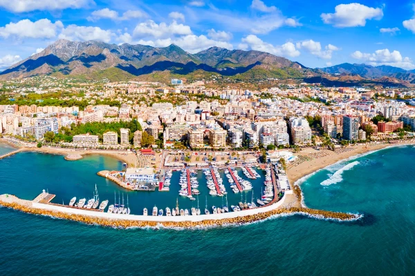 Una vista aerea panoramica di Marbella, che mostra il porto turistico, le spiagge e il paesaggio urbano costiero con le montagne della Sierra Blanca