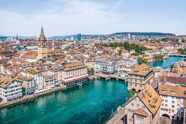 Zürich légi felvétele a Limmat folyóval, a piros tetős történelmi épületekkel és a kiemelkedő Szent Péter-templommal
