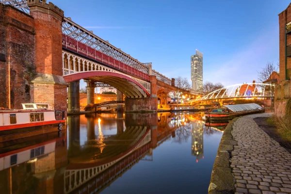 Paesaggio urbano di Manchester al tramonto con lo storico ponte ferroviario in mattoni rossi
