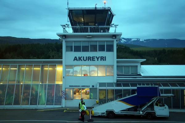Le bâtiment terminal de l'aéroport d'Akureyri au crépuscule avec montagnes en arrière-plan.