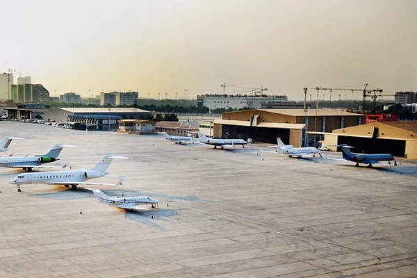 Hellblaues Flugzeug am Rollfeld des Flughafens Al Bateen mit sichtbaren Wartungshangars.