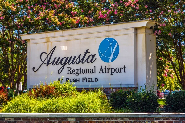 Un panneau blanc pour l'aéroport régional d'Augusta entouré de fleurs colorées.