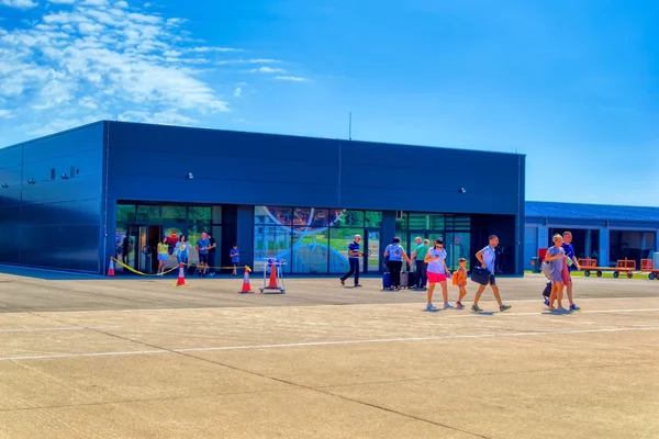 Children playing in an outdoor courtyard area next to a modern blue building at Banja Luka International Airport.