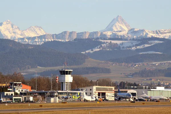 Terminal del Aeropuerto de Berna con picos alpinos nevados al fondo.