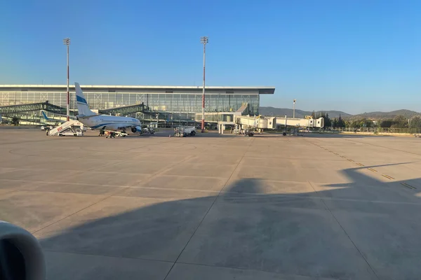 Ein Flugzeug am Terminal des Flughafens Milas-Bodrum mit Bodenfahrzeugen unter klarem Himmel.
