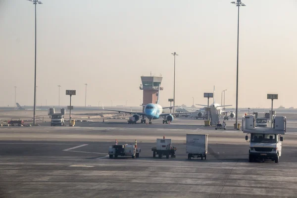Veicoli di supporto a terra e attrezzature al terminal dell'aeroporto internazionale del Cairo con torre di controllo e aereo parcheggiato visibili.