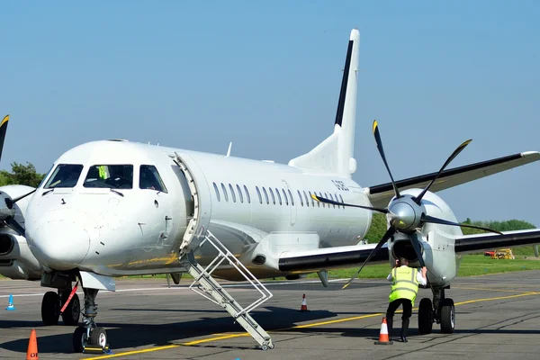Aeronave turbopropulsada estacionada en el Aeropuerto de Cambridge con escaleras de embarque.