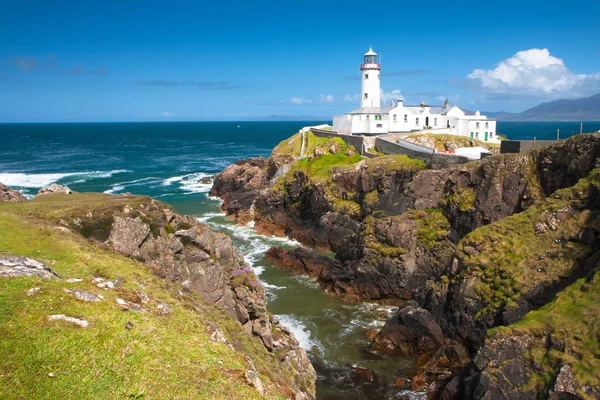 Faro blanco en acantilado rocoso con vistas al océano turquesa en Donegal, Irlanda.