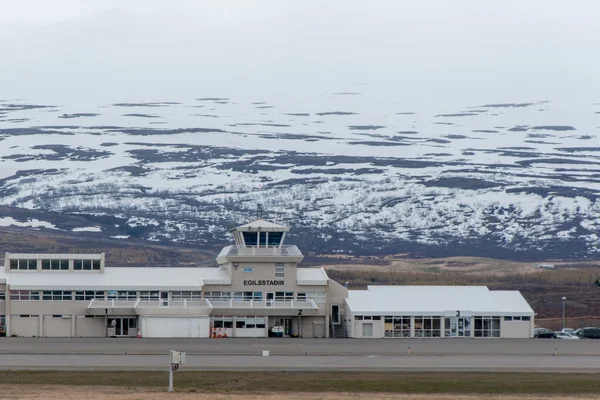 Terminal d'Egilsstaðir avec tour de contrôle contre les montagnes enneigées.