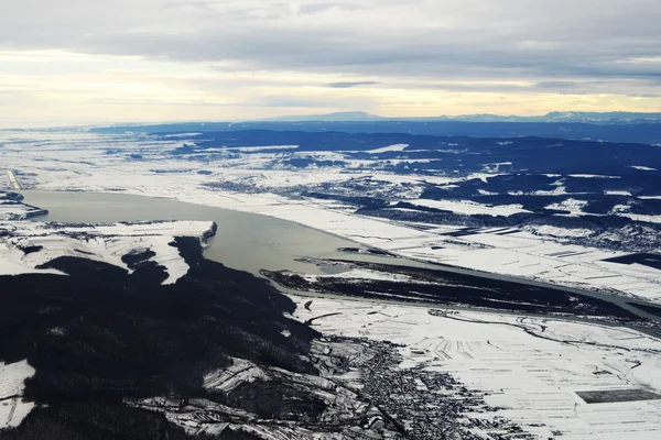Vue aérienne de l'aéroport George Enescu de Bacău en hiver entouré de montagnes.