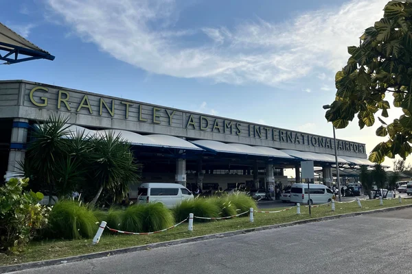 Terminal de l'aéroport international Grantley Adams avec façade blanche et végétation.
