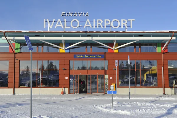 Bâtiment d'entrée de l'aéroport d'Ivalo avec façade en brique rouge dans un paysage enneigé.
