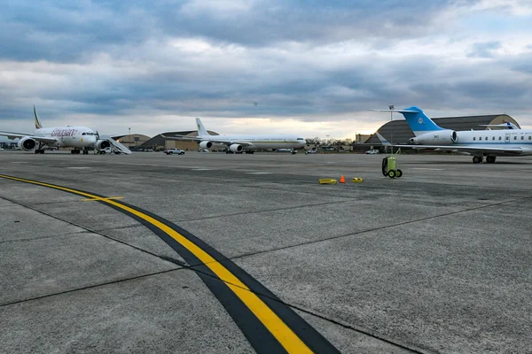 Plusieurs avions garés sur le tarmac de la base Andrews avec marquages de piste jaunes.