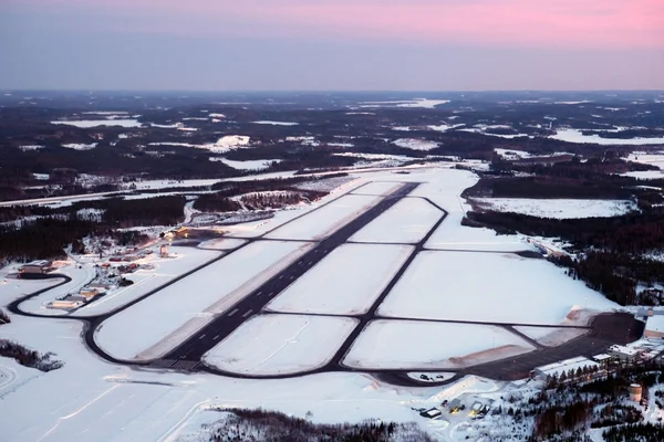Vue aérienne des pistes enneigées de l'aéroport de Jyväskylä en hiver entourées de forêts et lacs gelés.