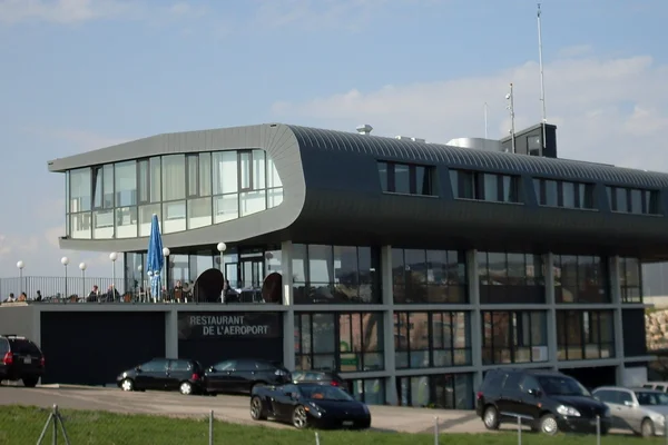 Terminal moderna del Aeropuerto de Lausana Blécherette con arquitectura curva negra y vidrio.