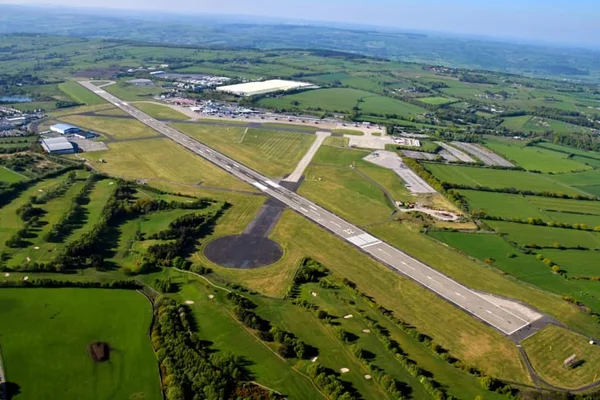 Aerial view of Leeds Bradford Airport showing two parallel runways surrounded by green fields and agricultural land in Yorkshire, England.