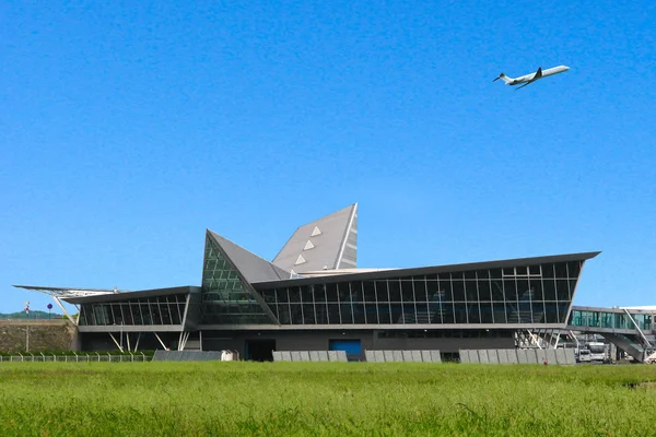 Terminal del Aeropuerto de Lille con diseño angular distintivo y avión volando bajo cielo azul.
