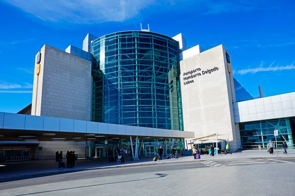 Modern terminal building of Lisbon Humberto Delgado Airport with cylindrical glass structure, white facades, and clear blue sky above.
