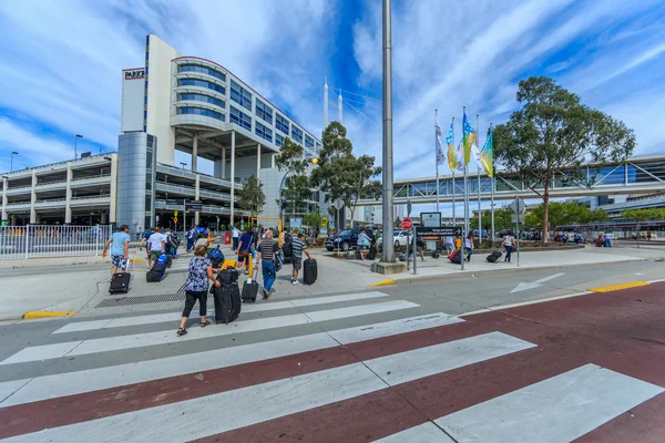 Passeggeri con bagagli attraversano le strisce pedonali al terminal dell'Aeroporto di Melbourne.