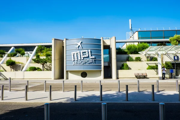 Vista exterior del edificio terminal del Aeropuerto Montpellier-Méditerranée con señalización azul.