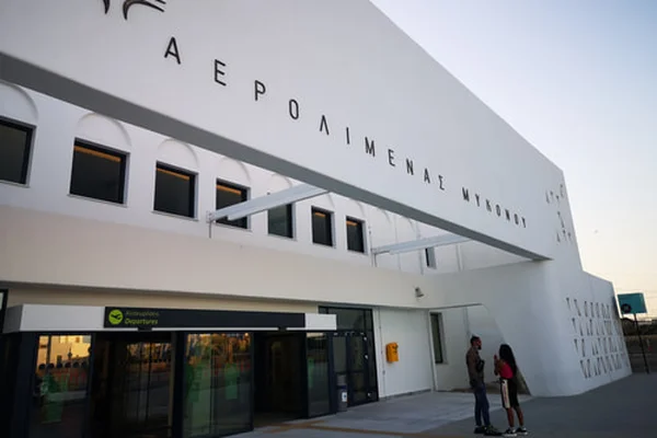 Exterior view of Mykonos Airport terminal building with white curved architecture and horizontal windows.