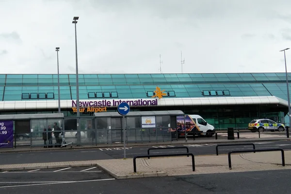 Terminal del Aeropuerto Internacional de Newcastle con fachada turquesa moderna de vidrio.