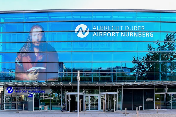 Entrada del Aeropuerto Albrecht Dürer Nürnberg con gran retrato en fachada de vidrio.