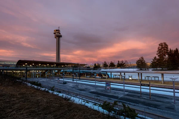 Vue crépusculaire de la tour de contrôle d'Oslo Airport au-dessus du terminal avec pistes mouillées.