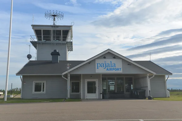 Terminal de l'aéroport Pajala avec tour de contrôle sous ciel partiellement nuageux.