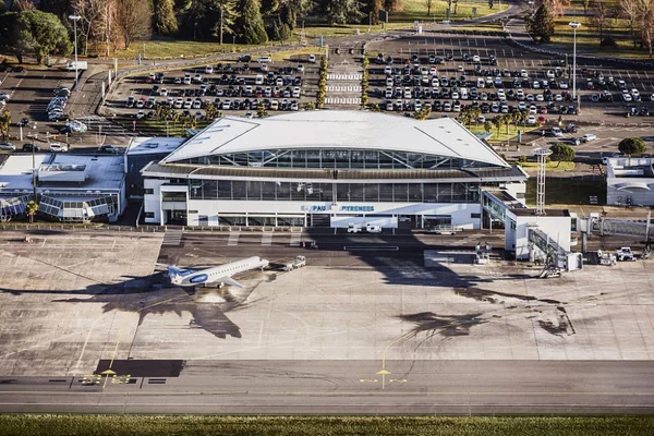 Vista aérea del edificio terminal del Aeropuerto Pau Pyrénées con estacionamiento y tarmac.