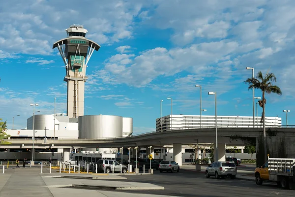 Torre di controllo e terminal dell'Aeroporto di Perth con palma e cielo azzurro.