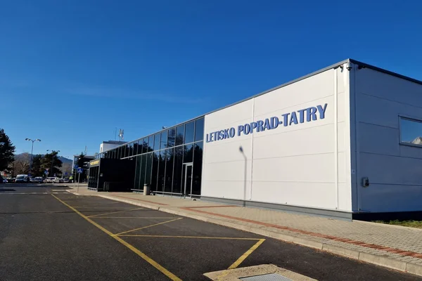 Vue extérieure du terminal de l'aéroport Poprad-Tatry avec façade blanc et noir sous ciel bleu.