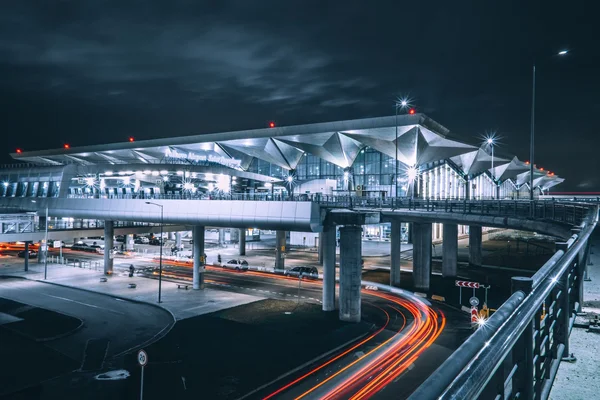 Terminal de l'aéroport Pulkovo la nuit avec toit blanc illuminé et traces lumineuses de véhicules.