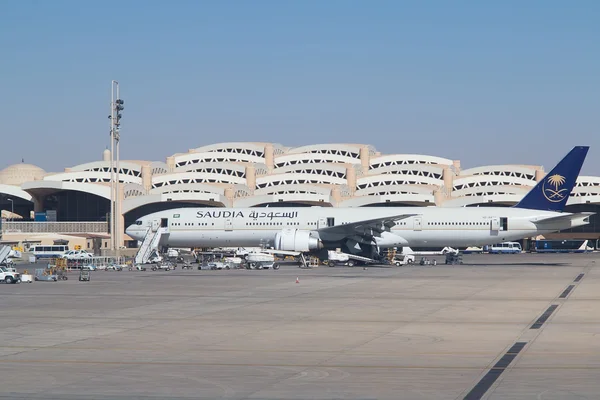 Boeing 777 der Saudia am Terminal des Flughafens King Khalid International mit Bodenfahrzeugen und Infrastruktur.