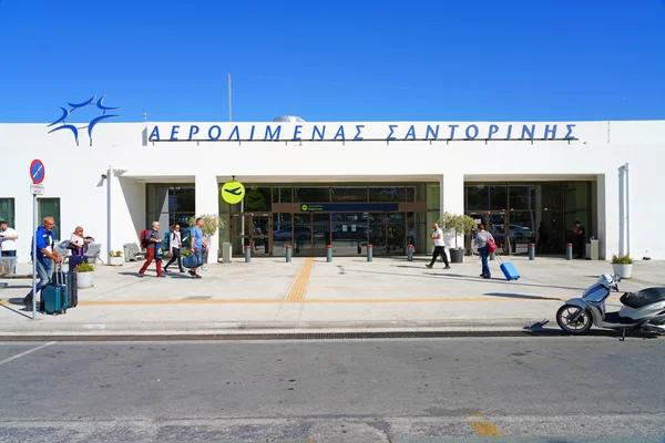 Exterior view of Santorini Airport terminal building with passengers and luggage outside on a sunny day.