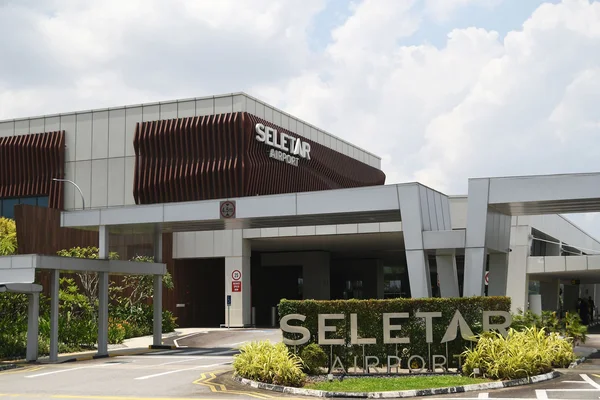 Терминал аэропорта Селетар с современной архитектурой и коричневым панелями.